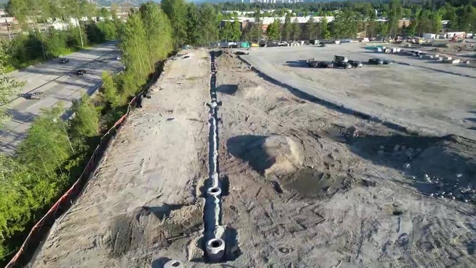 Drone view of a storm main with manholes being installed through a cleared site